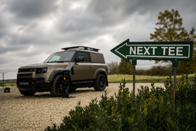 Defender 90 auf dem Golfplatz neben einem Wegweiser zum nächsten Abschlag
